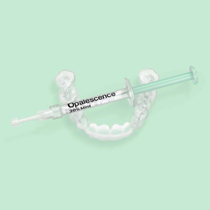 Opalescence take-home teeth whitening gel syringe with clear dental trays on a mint green background.