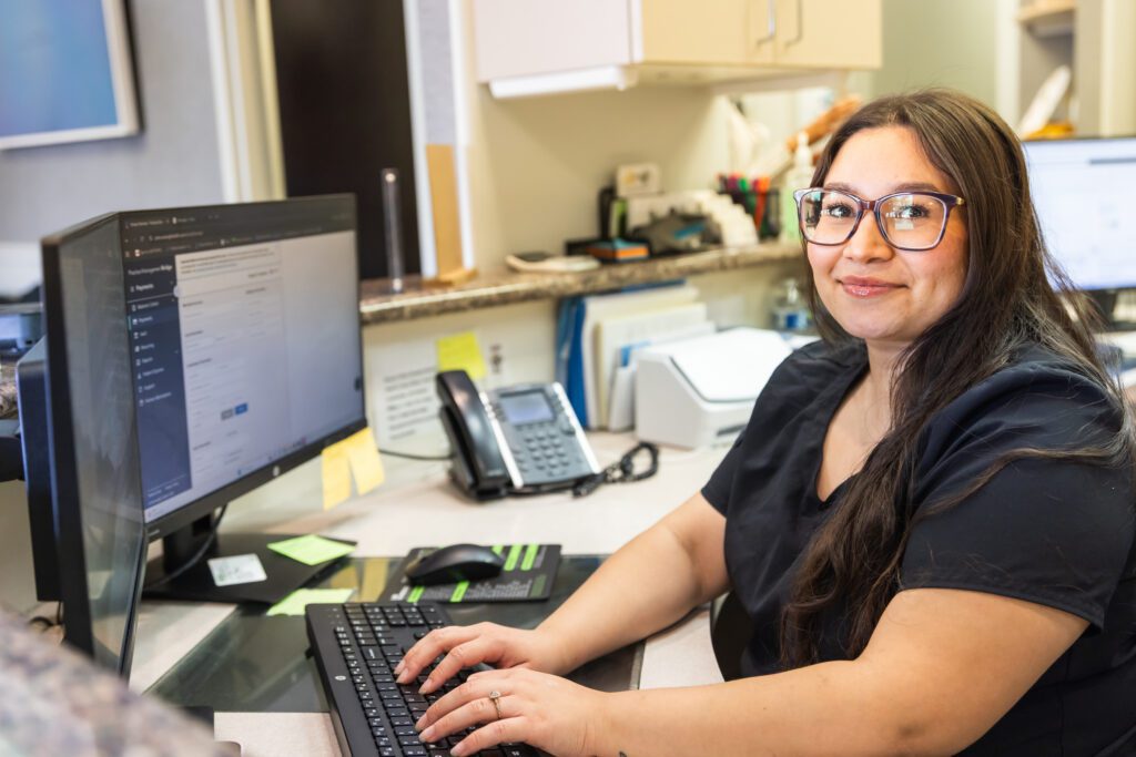 ental receptionist working at a computer workstation in a modern dental practice.