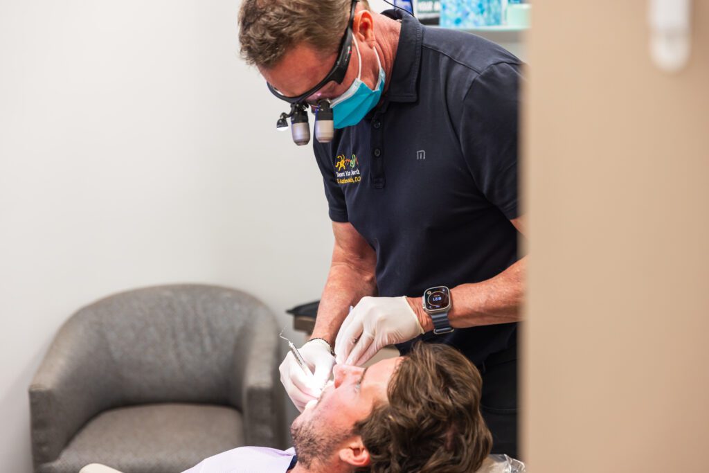 Dentist performing a dental procedure on a patient in a treatment room at a dental clinic.